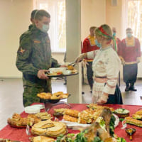 民族衣装の女性から料理を取り分けてもらう（Image：ロシア国防省）