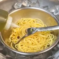 茹で上げたパスタをボウルに入れ、氷で冷やしながらオイルと混ぜ手早く冷やす（麦ライスさん提供）