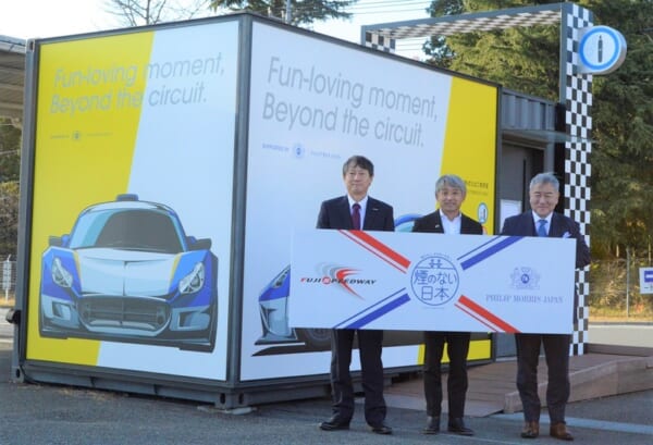 富士スピードウェイに設置された加熱式たばこ専用喫煙所前での片山右京さん（中）ら