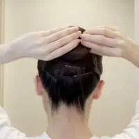 シニヨンがなるべく平たくなるように、指を使ってシニヨンの厚みを薄くします