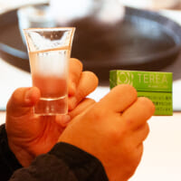 「Sake Marriage」第1弾となる、石川の純米酒「加賀鶴」と「テリア イエロー メンソール」を手に持つ岩崎さん