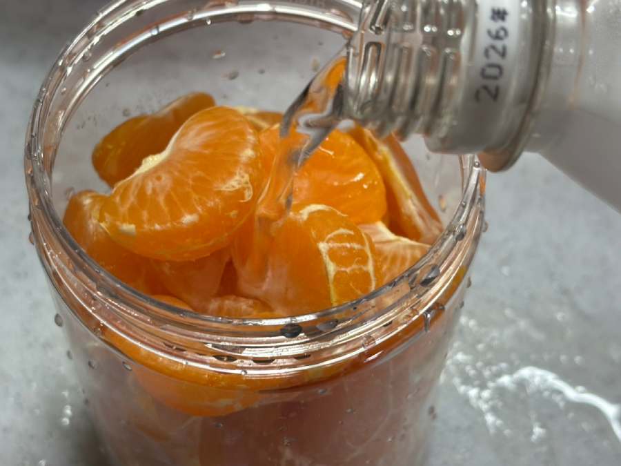 みかんを密閉容器に移し、強炭酸水を注ぎ入れる